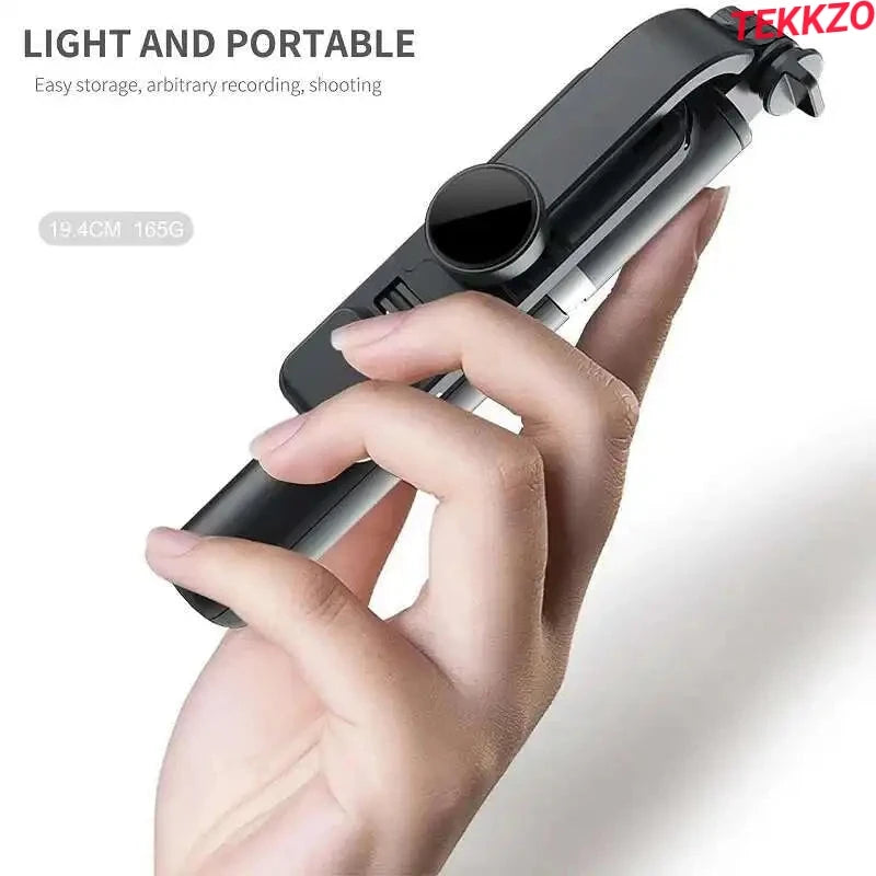 Hand holding a compact black portable selfie stick with a phone holder, lightweight and easy to carry